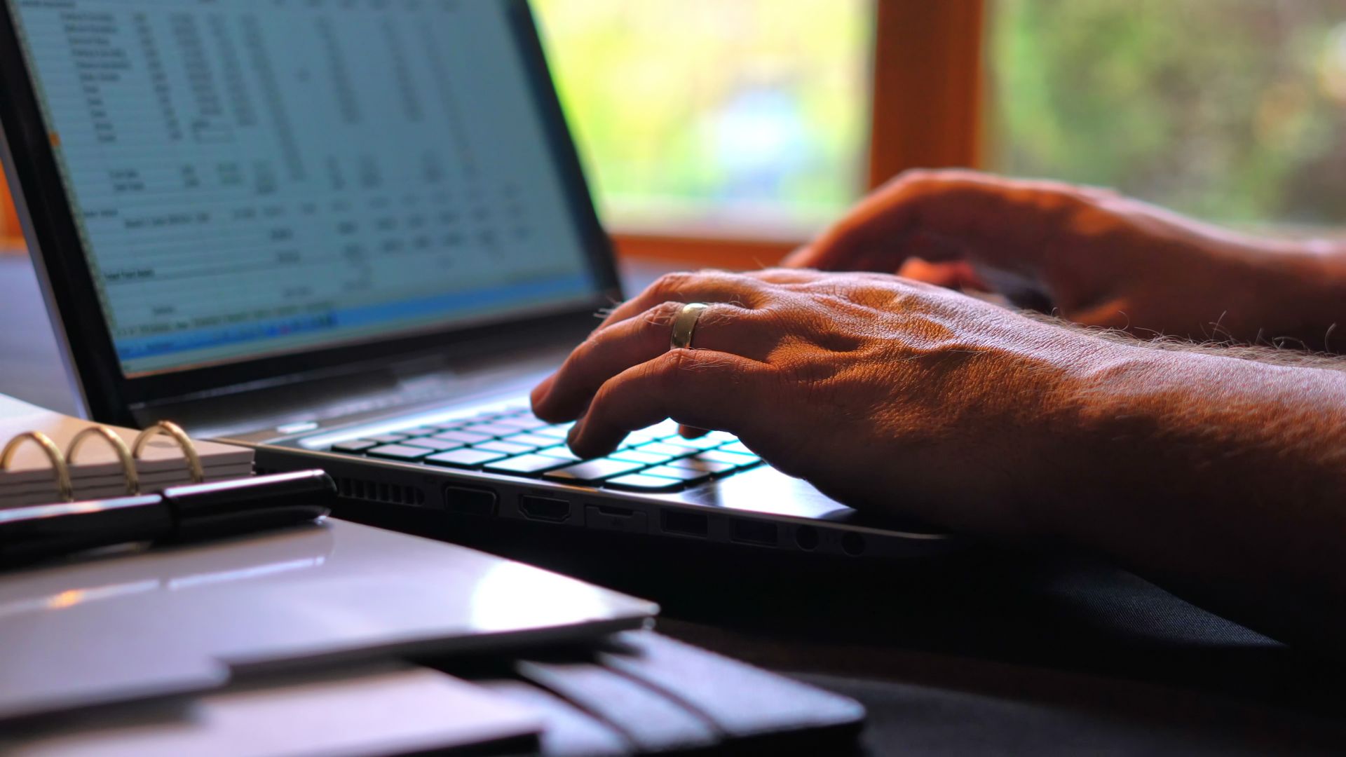 Hands Typing on A Laptop Keyboard, with A Notebook Visible in The Foreground — Wright Partners in Brewarrina, NSW