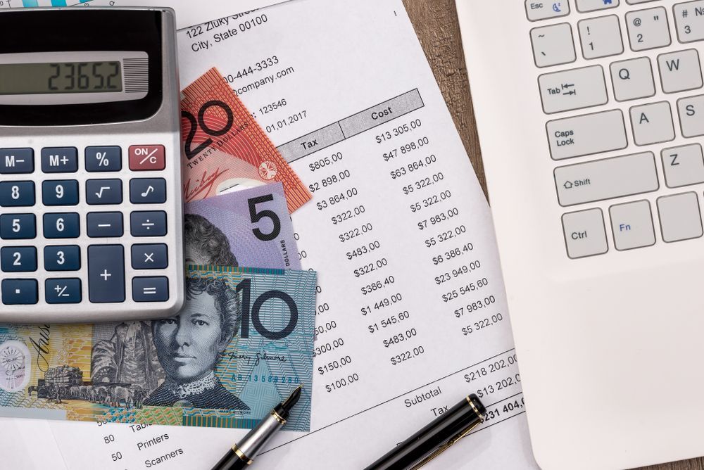 Calculator, Australian Currency, and Financial Documents on A Desk Next to A Laptop — Wright Partners in Walgett, NSW