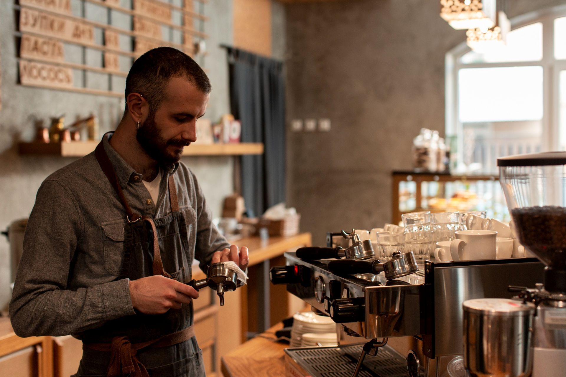 Barista preparing espresso at a café counter with coffee machines and glassware