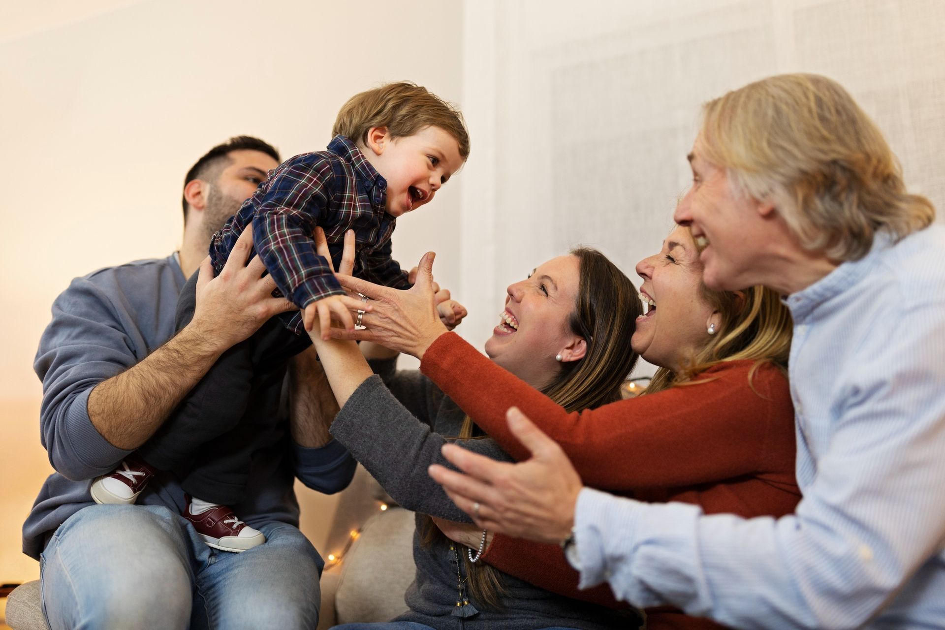 Family playing and laughing together on a couch indoors