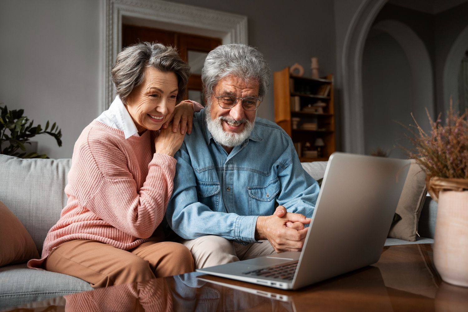 Smiling couple on a couch using a laptop in a cozy living room