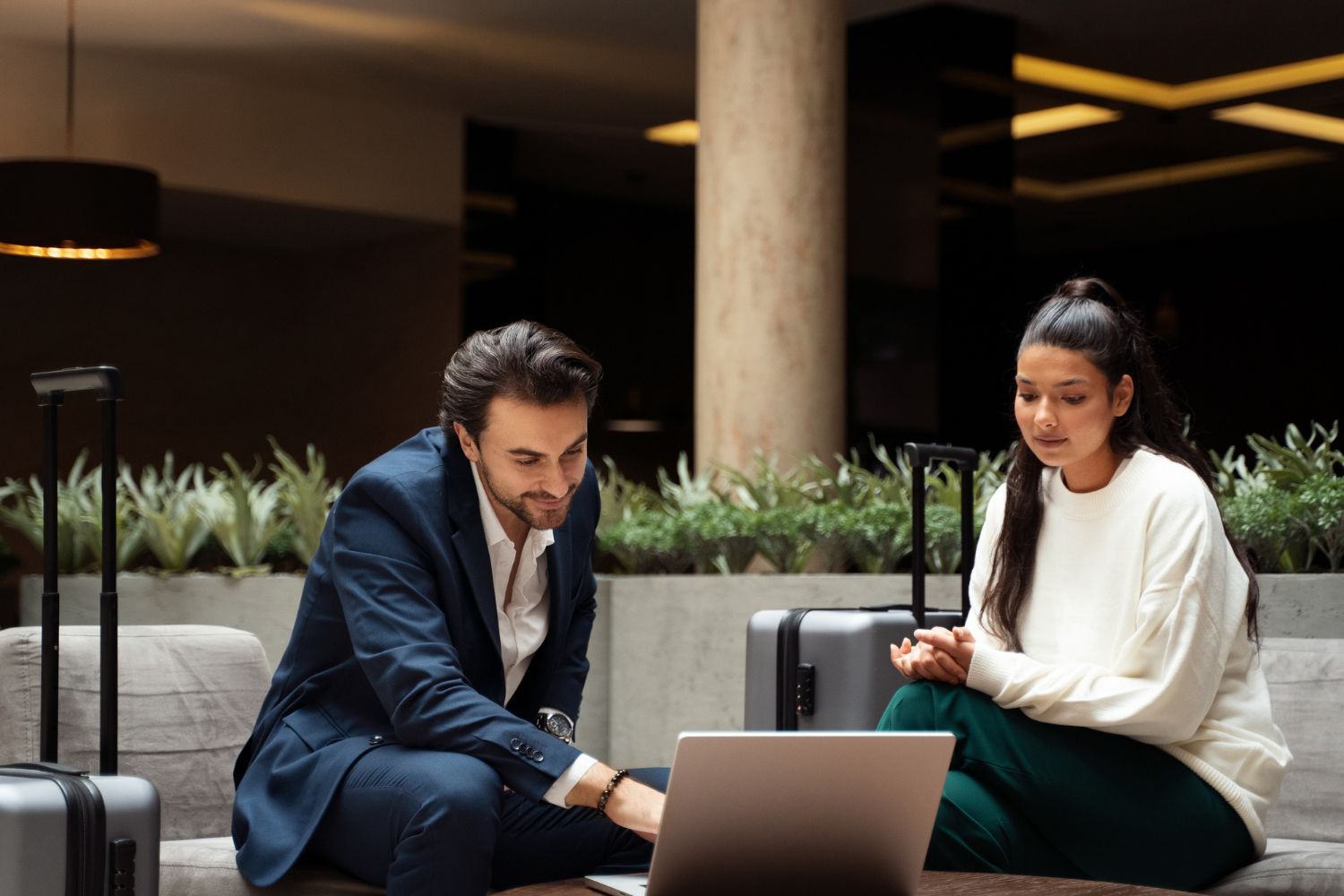 Two people sitting on a couch, working together on a laptop in a modern lounge.