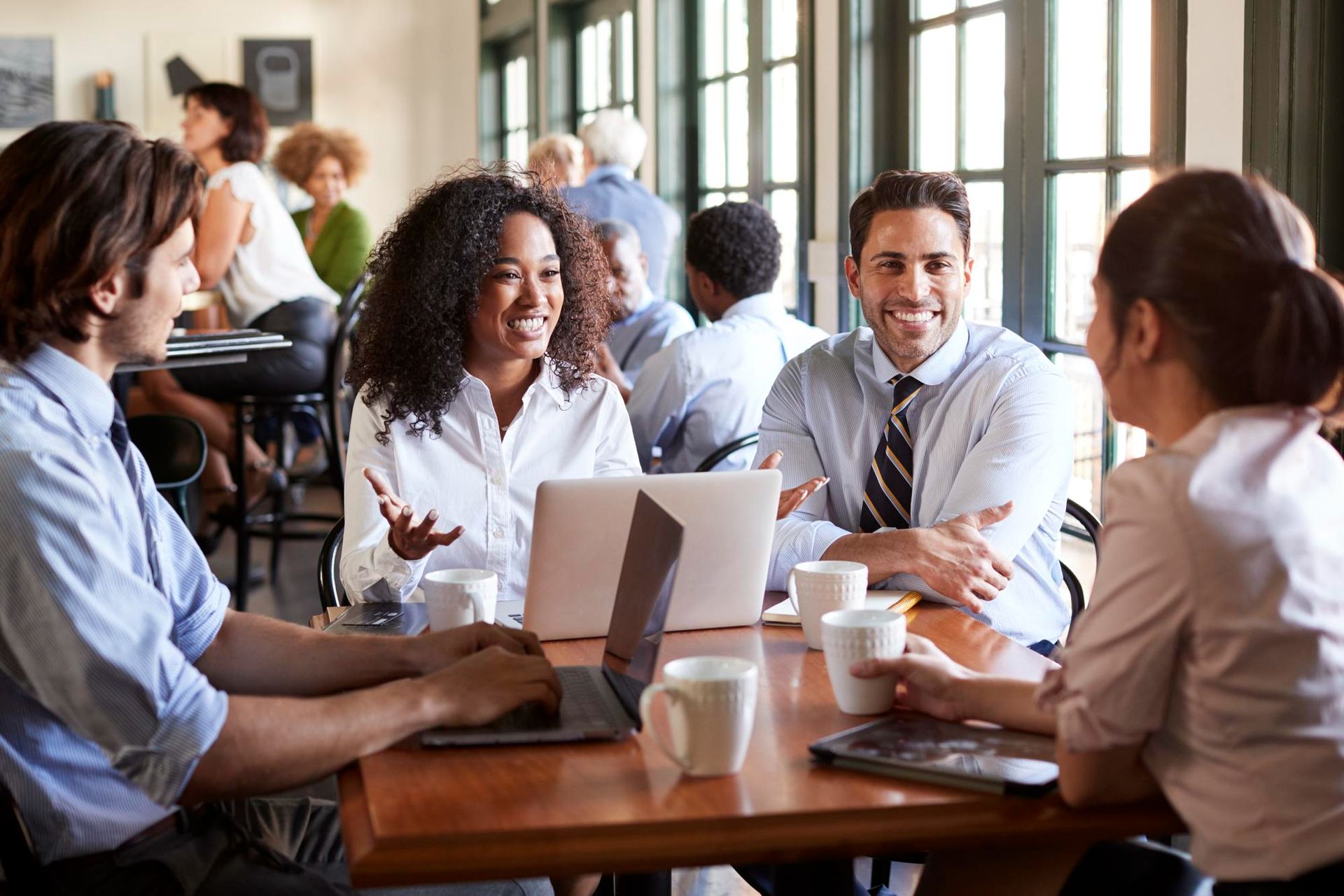 Coworkers talking around a laptop at a conference table in a bright office