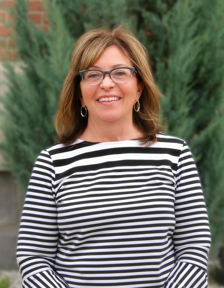 Smiling person in glasses wearing a black-and-white striped top outdoors with green foliage background