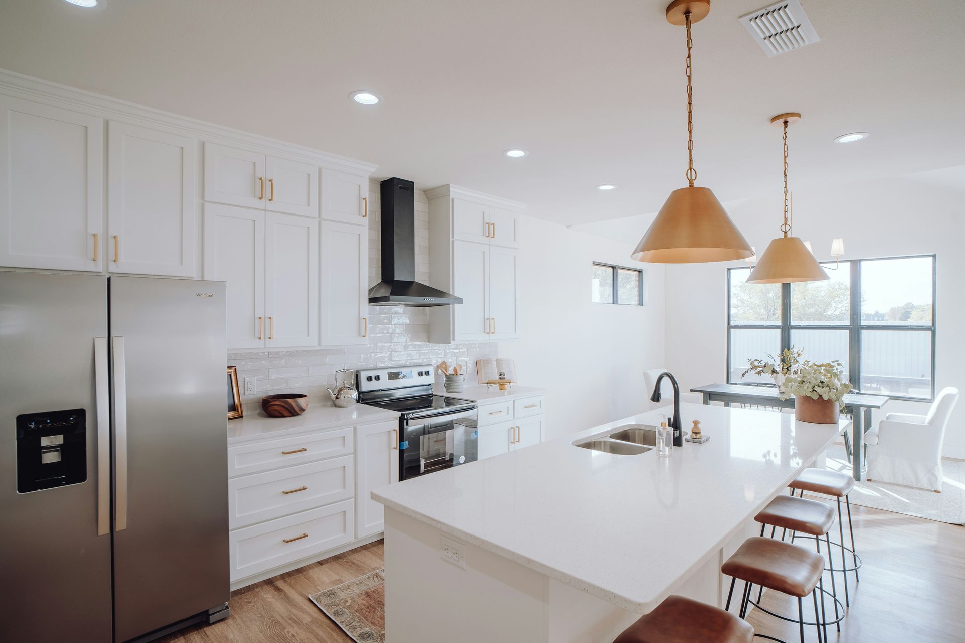 Bright modern kitchen with white cabinets, stainless appliances, island, and copper pendant lights