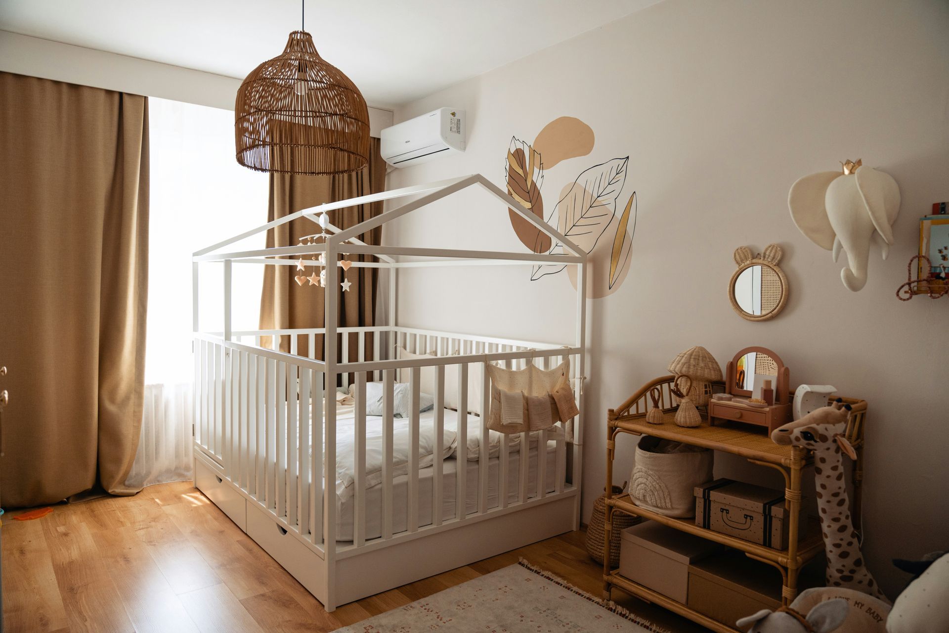 White crib in a cozy nursery with warm wood accents, woven chandelier, and animal wall decor