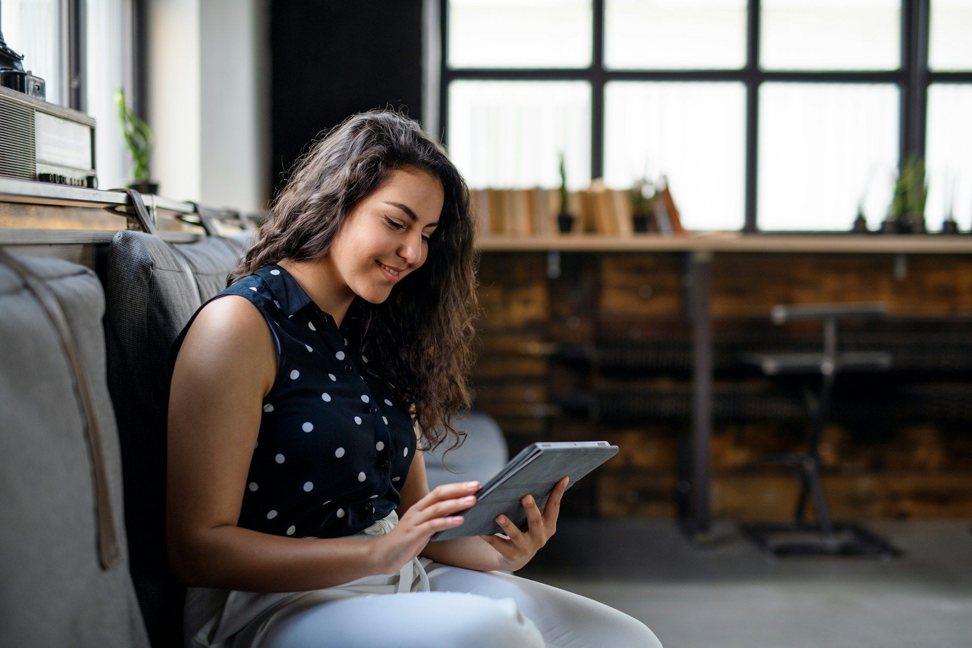 Woman sitting on a couch using a tablet in a bright living room