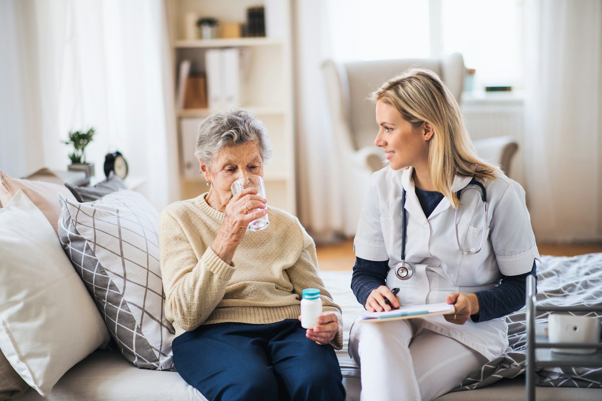 Healthcare worker speaking with patient on a couch in a bright living room