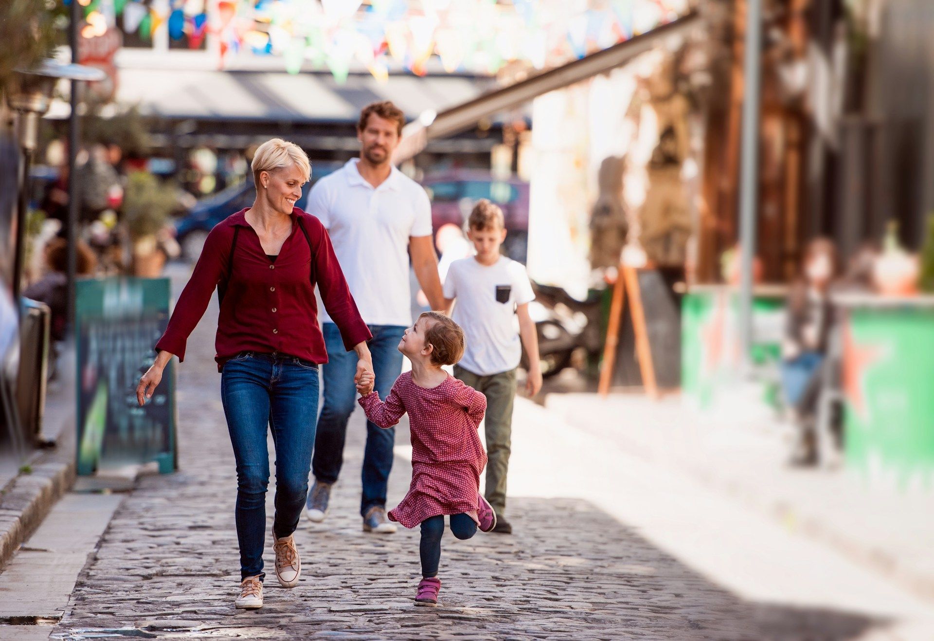 Family walking together on a cobblestone street in a sunny market area