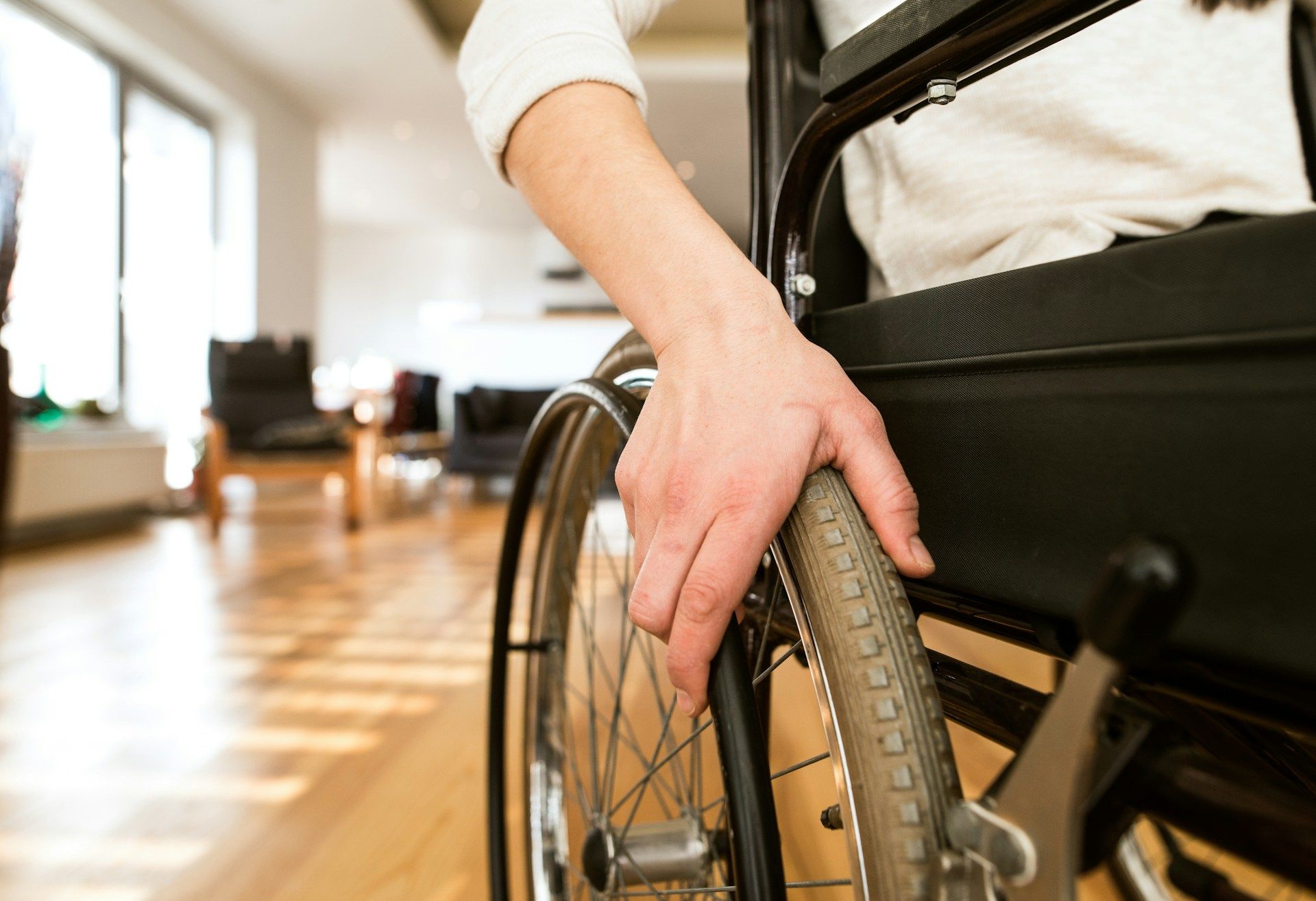 Hand resting on a wheelchair wheel in a bright indoor room