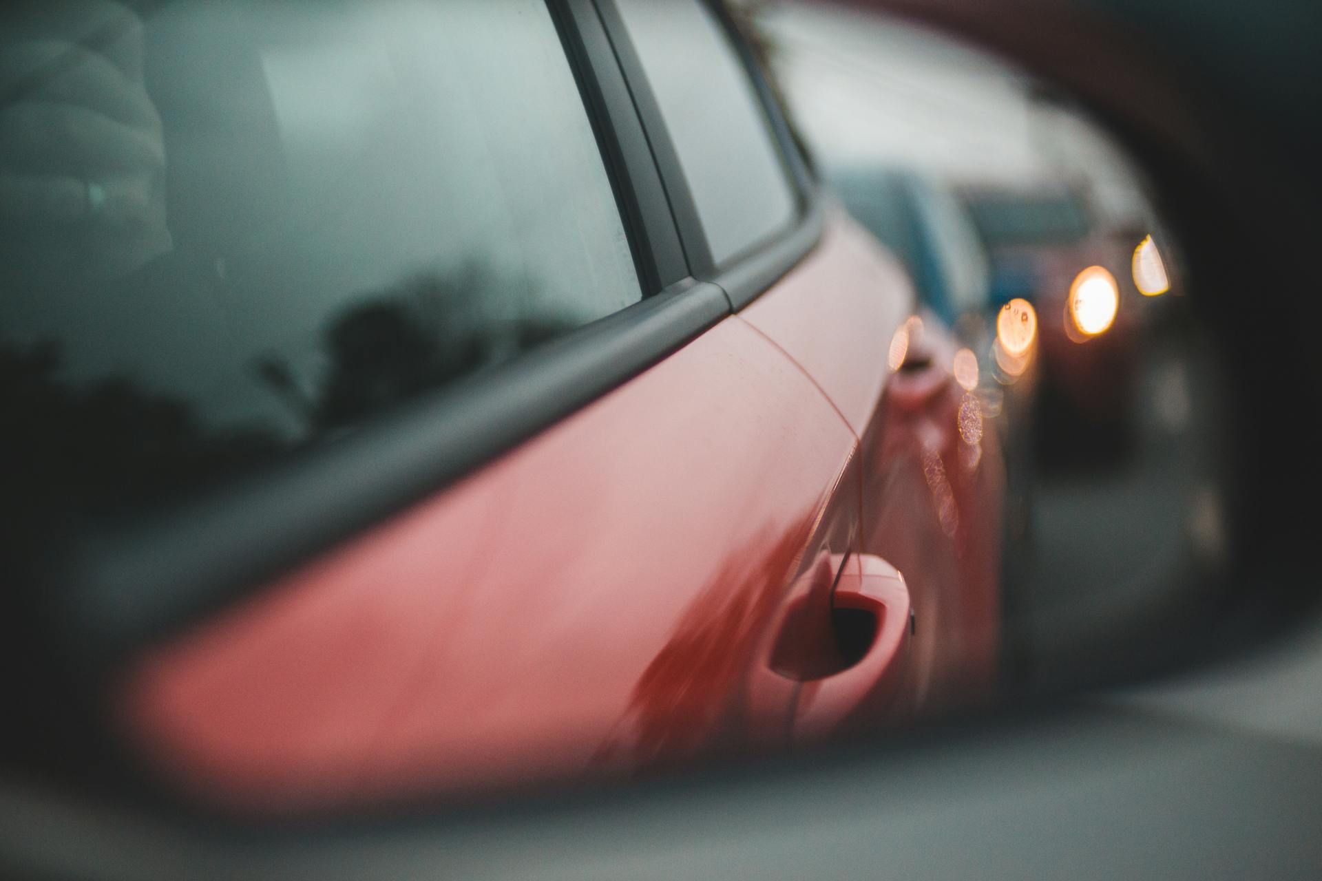 Red car in a line of vehicles, with blurred headlights behind it.