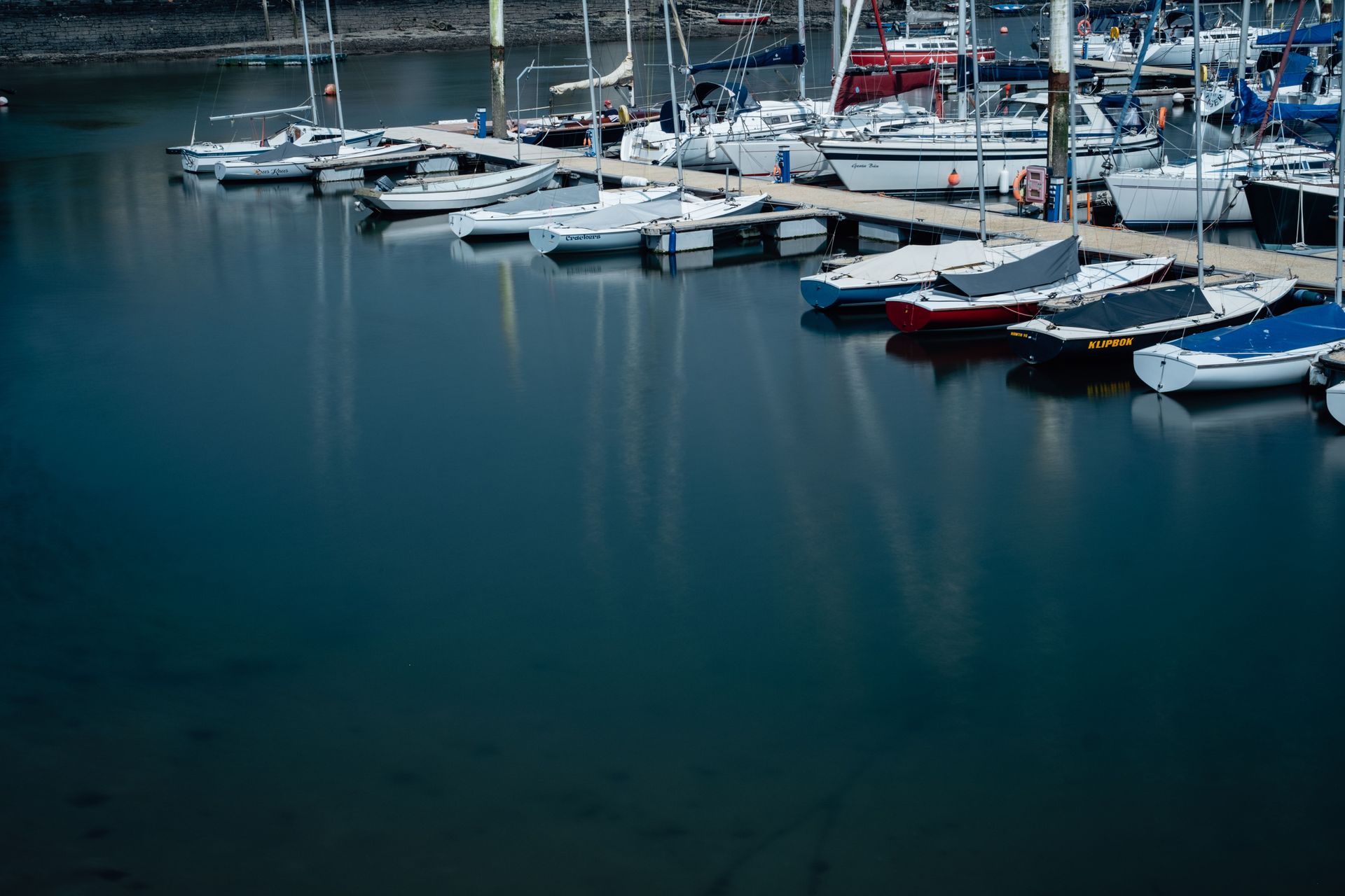 Marina with white sailboats and yachts docked on calm blue water