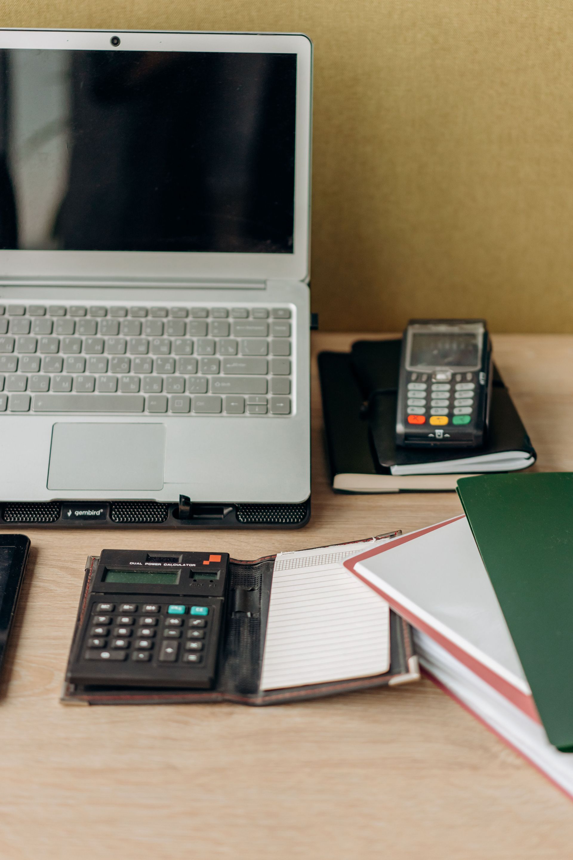 Desk with a laptop, calculator, notebook, and stacked books in an office setting