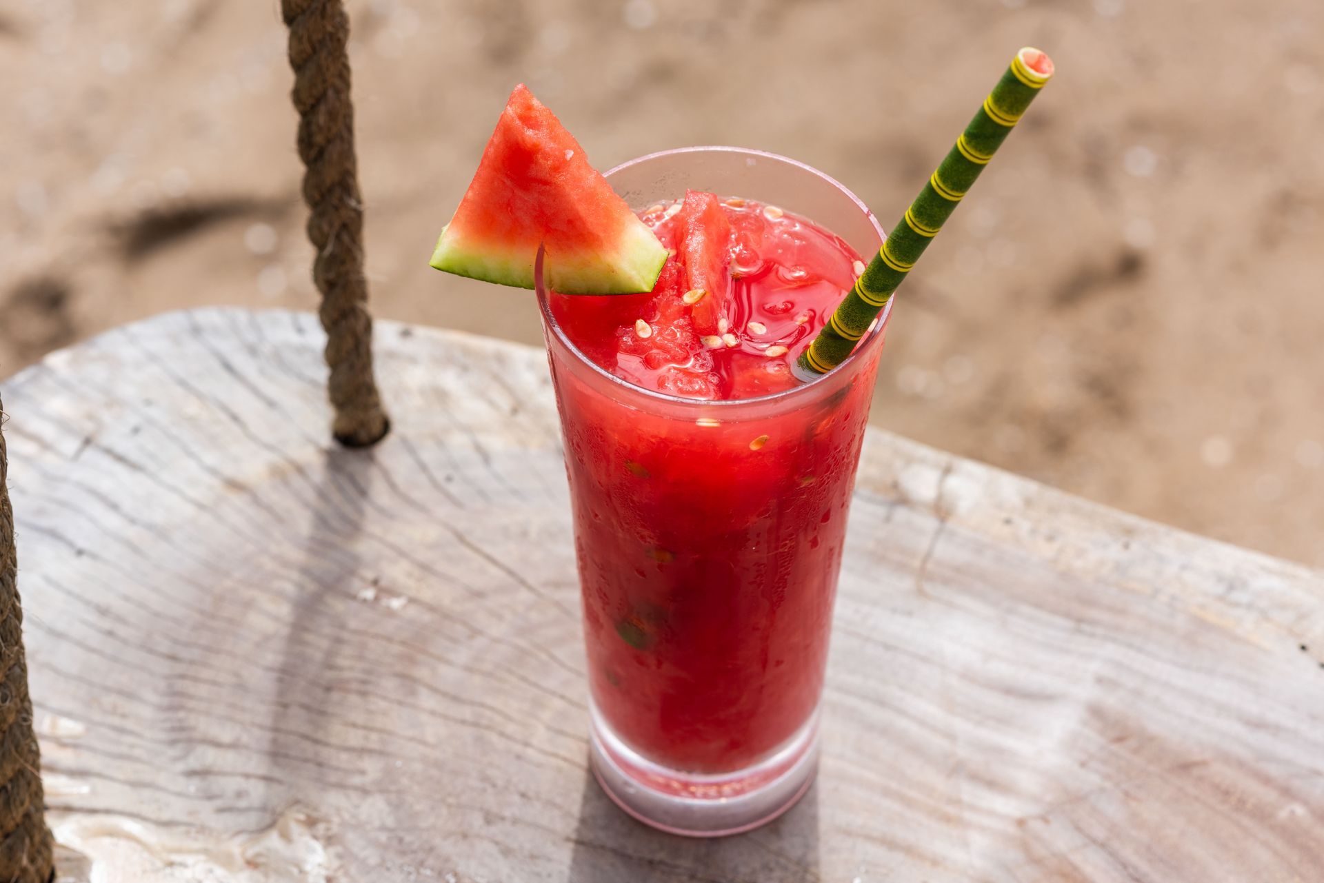 Mujer sonriendo en un bar tropical con una bebida de piña, frutas y un ambiente de techo de paja.