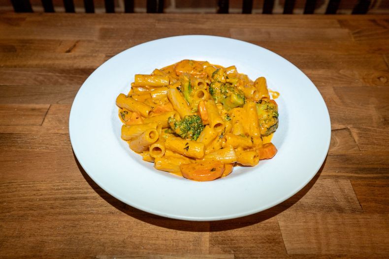 Pasta dish with rigatoni, broccoli, and carrots in a creamy orange sauce, served on a white plate.