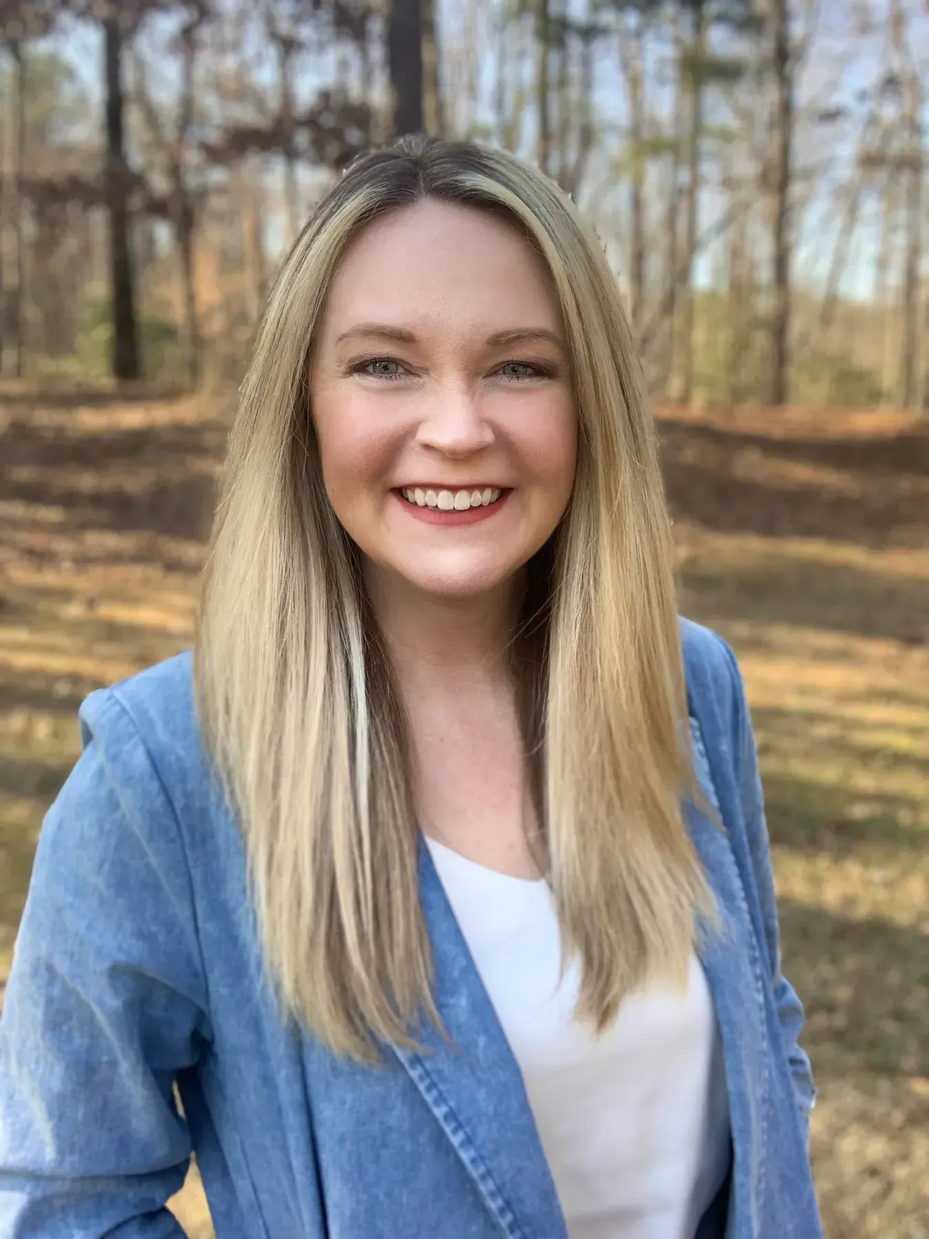 A woman in a blue jacket and white shirt is smiling for the camera.