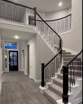 Spacious foyer with curved staircase, hardwood floors, and a view into the adjacent living area.