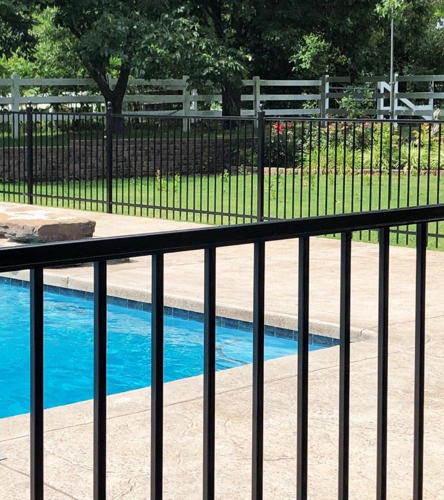a black fence surrounds a swimming pool 