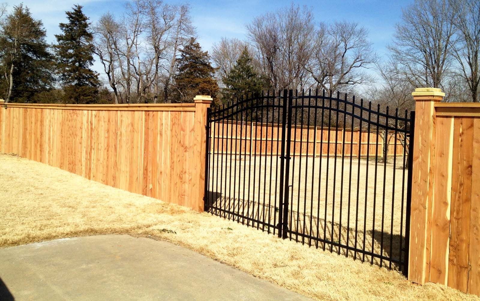 a wooden fence with a metal gate in front of it