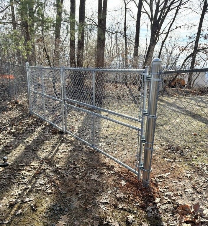 a black chain link fence is surrounded by trees in a yard .