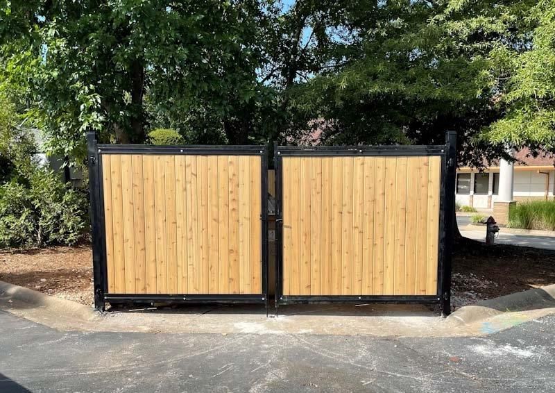 A wooden fence with a black frame around a dumpster