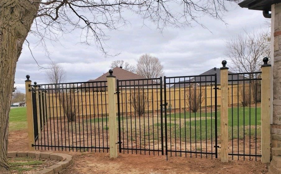 a wrought iron fence with a wooden post in front of a house .