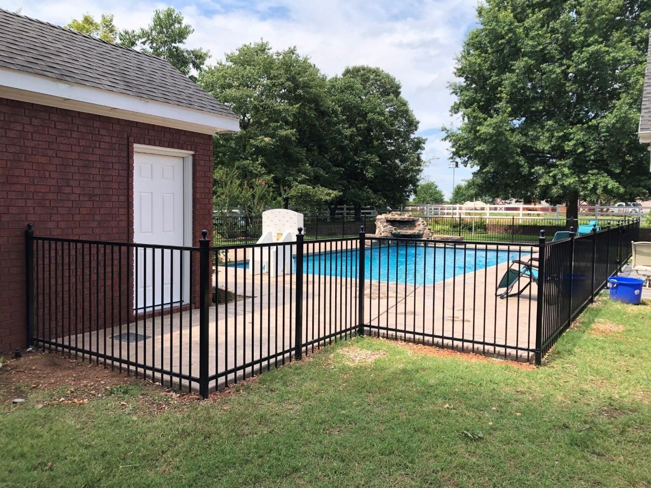 a black fence surrounds a swimming pool in a backyard