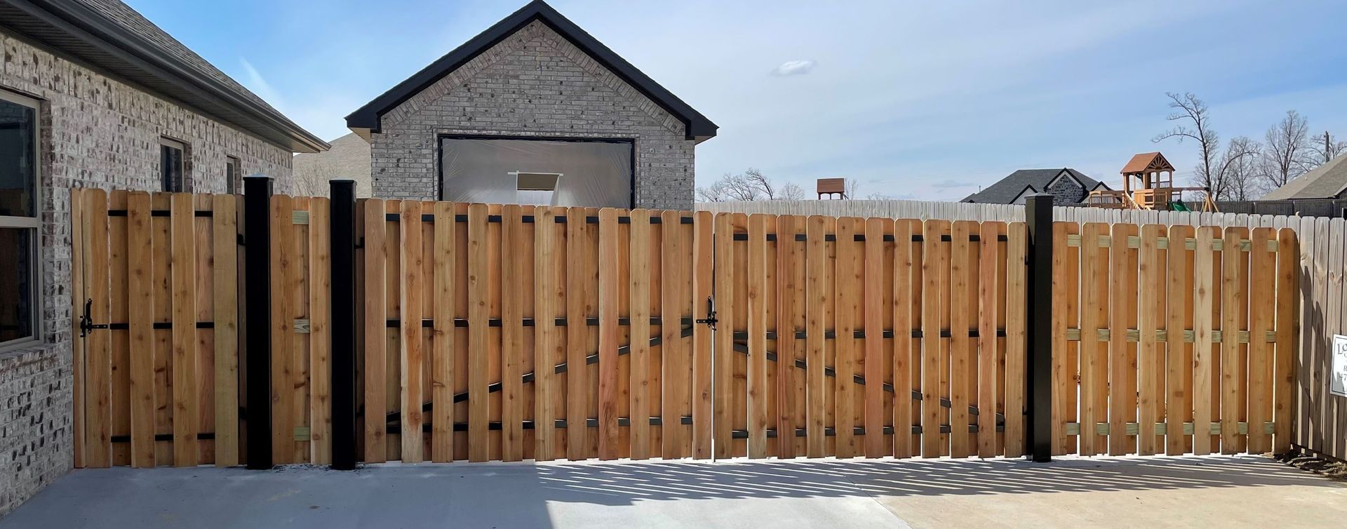 A wooden fence is sitting in front of a brick house.