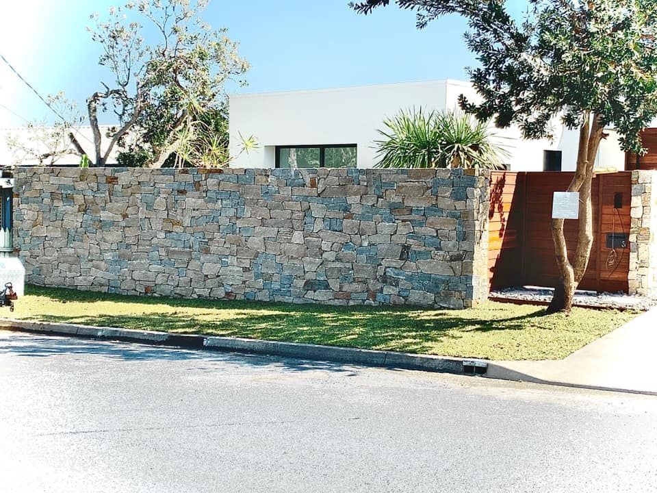 A Modern White House Partially Obscured by A Rustic Stone Wall  — Creative Landscapes Coffs Harbour in Korora, NSW