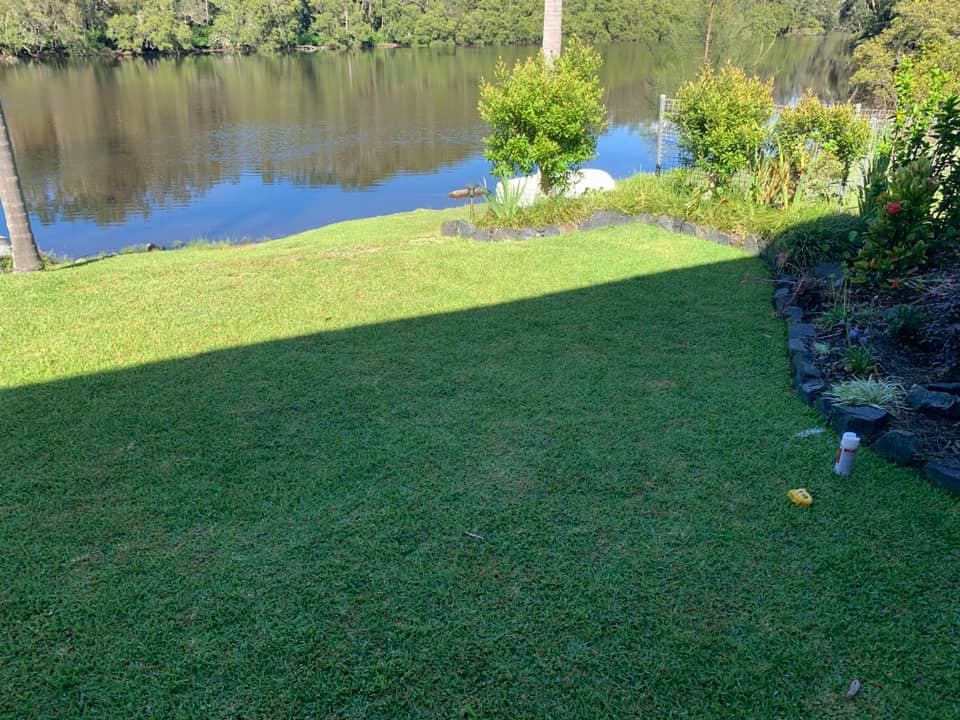 A Lush Green Lawn Leading to A Calm River — Creative Landscapes Coffs Harbour in Sandy Beach, NSW