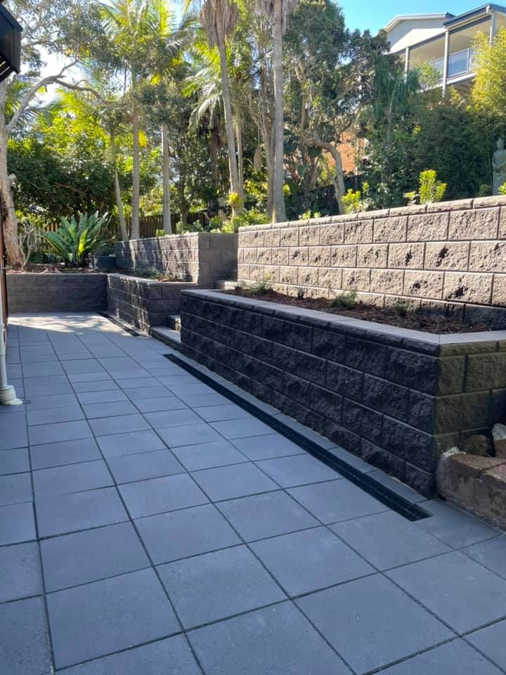 A Paved Patio Area Bordered by Multi-Level Grey Stone  — Creative Landscapes Coffs Harbour in Korora, NSW