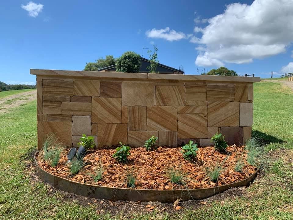 A Tan Sandstone Wall Sits Behind a Mulched Garden Bed  — Creative Landscapes Coffs Harbour in Korora, NSW