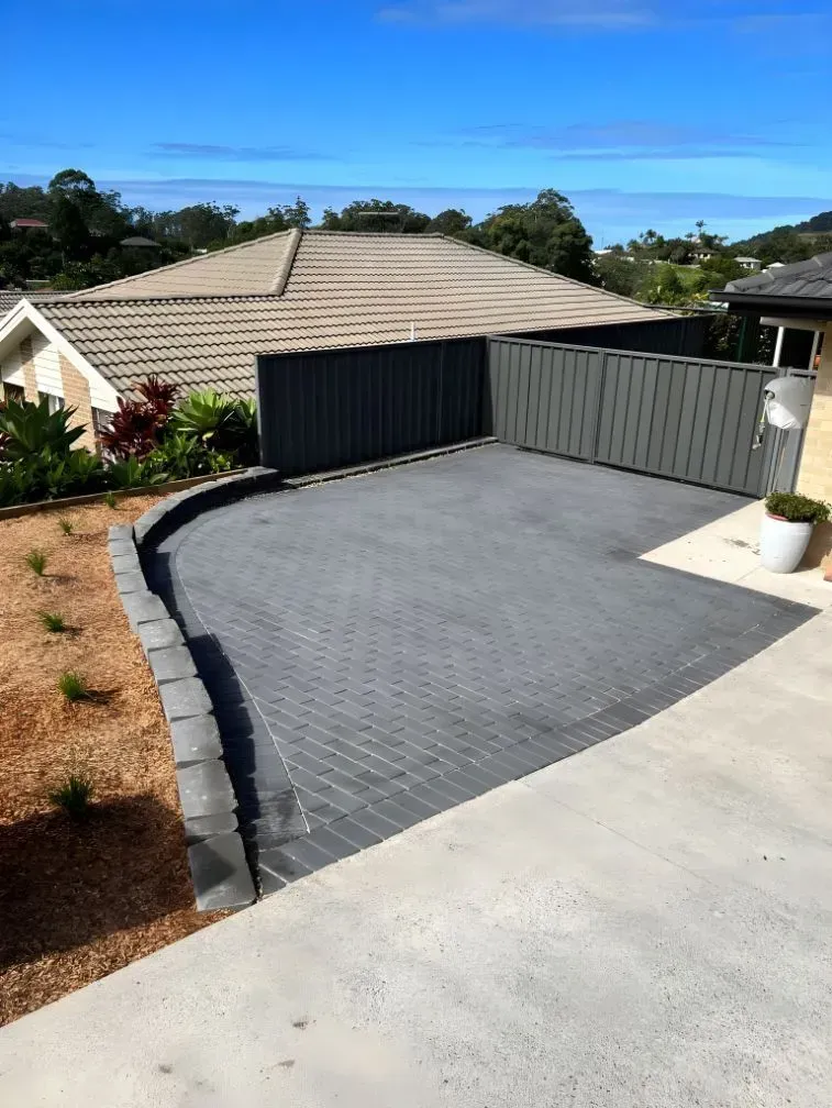 A Paved Driveway Area with A Charcoal Retaining Wall — Creative Landscapes Coffs Harbour in Sapphire Beach, NSW