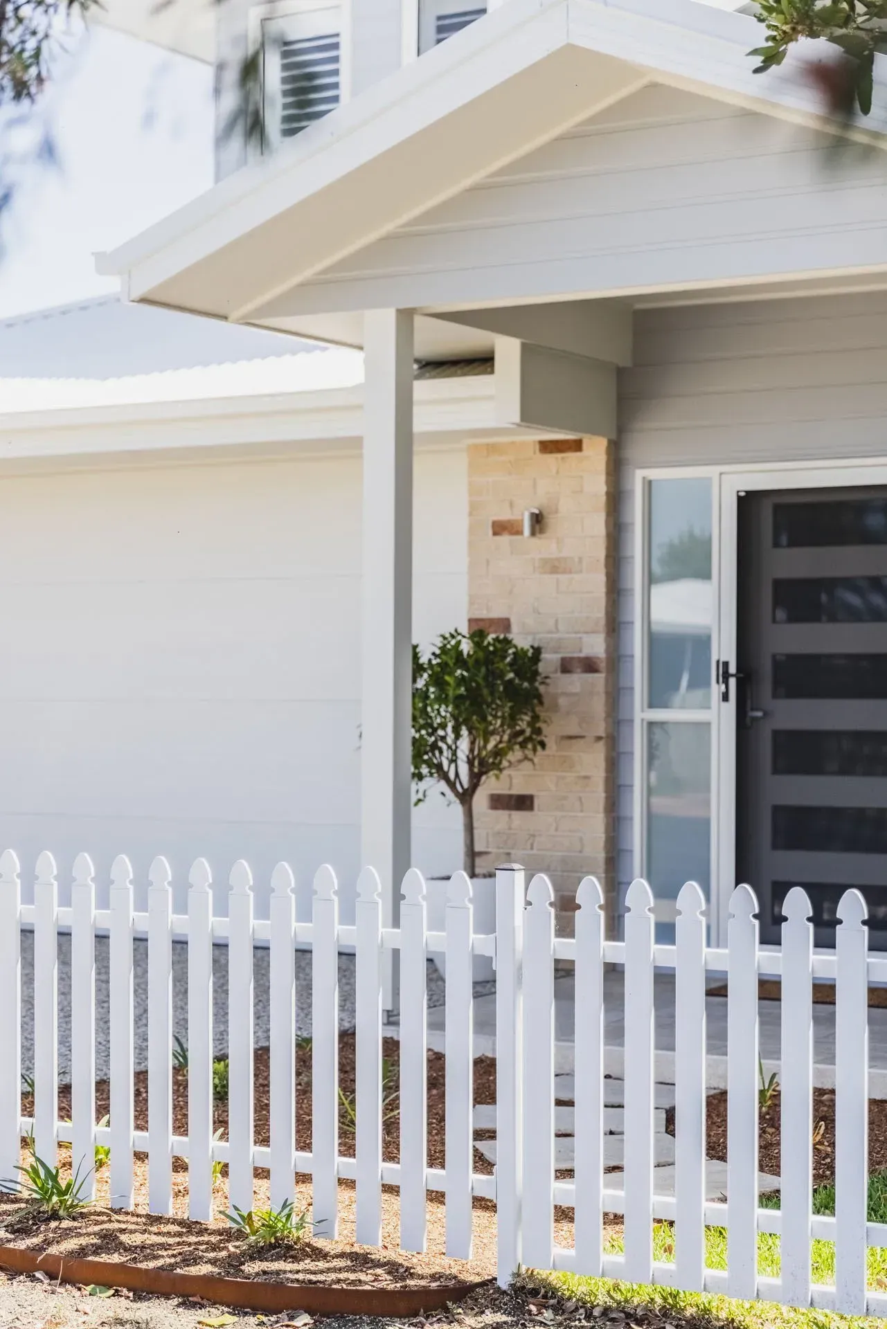 A White Picket Fence Stands in Front of A Modern Home  — Creative Landscapes Coffs Harbour in Korora, NSW