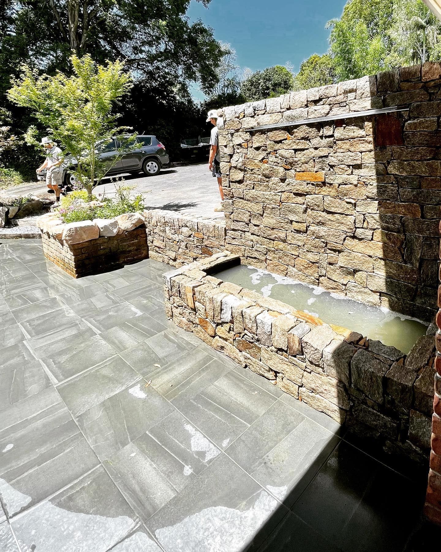 A Stone Water Feature and A Planter on A Grey Patio — Creative Landscapes Coffs Harbour in Sawtell, NSW