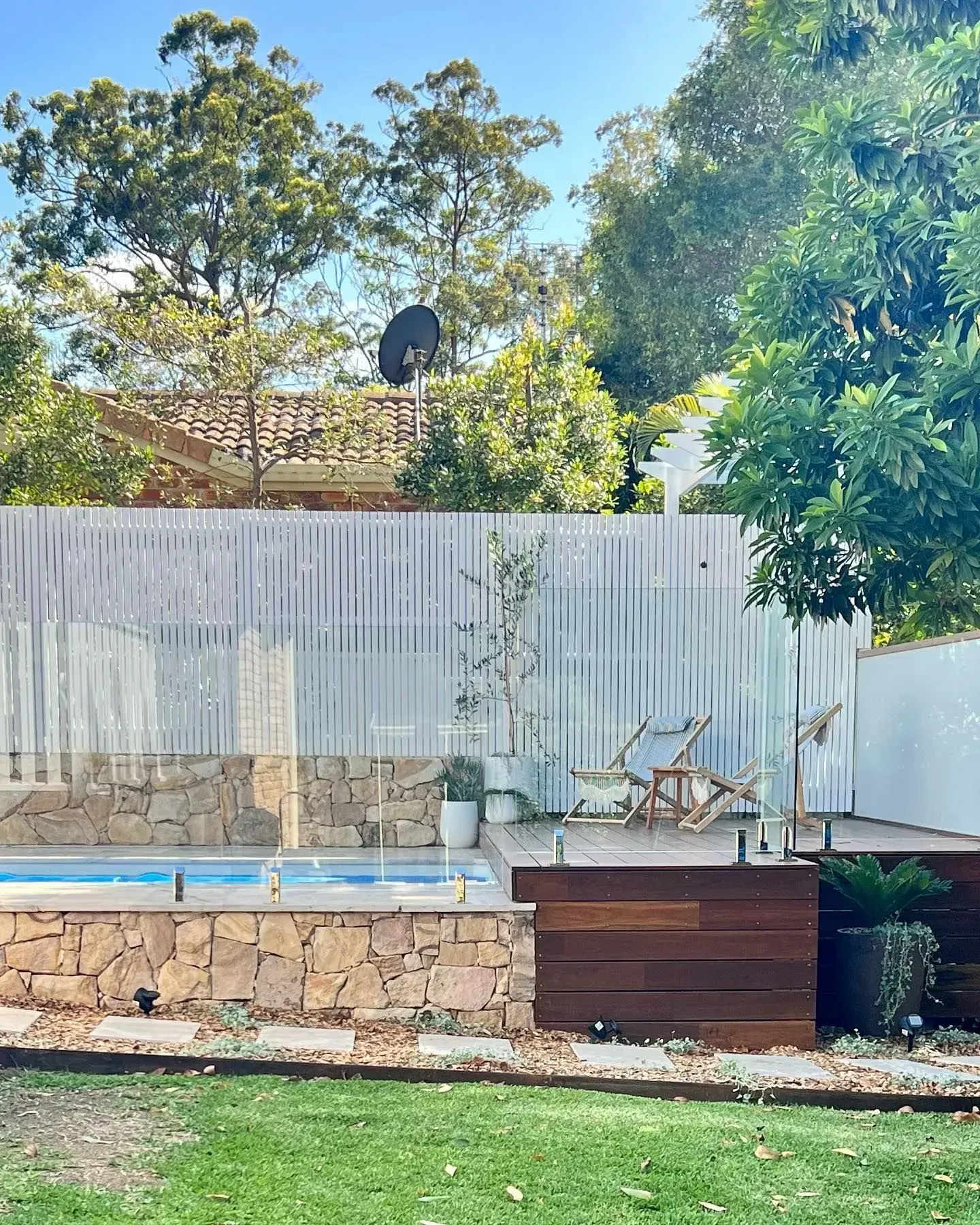 A Swimming Pool with A Stone Base and Wooden Deck  — Creative Landscapes Coffs Harbour in Korora, NSW