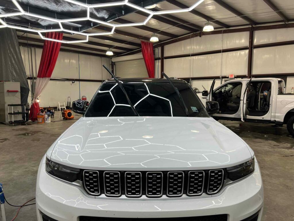 A white jeep is parked in a garage.