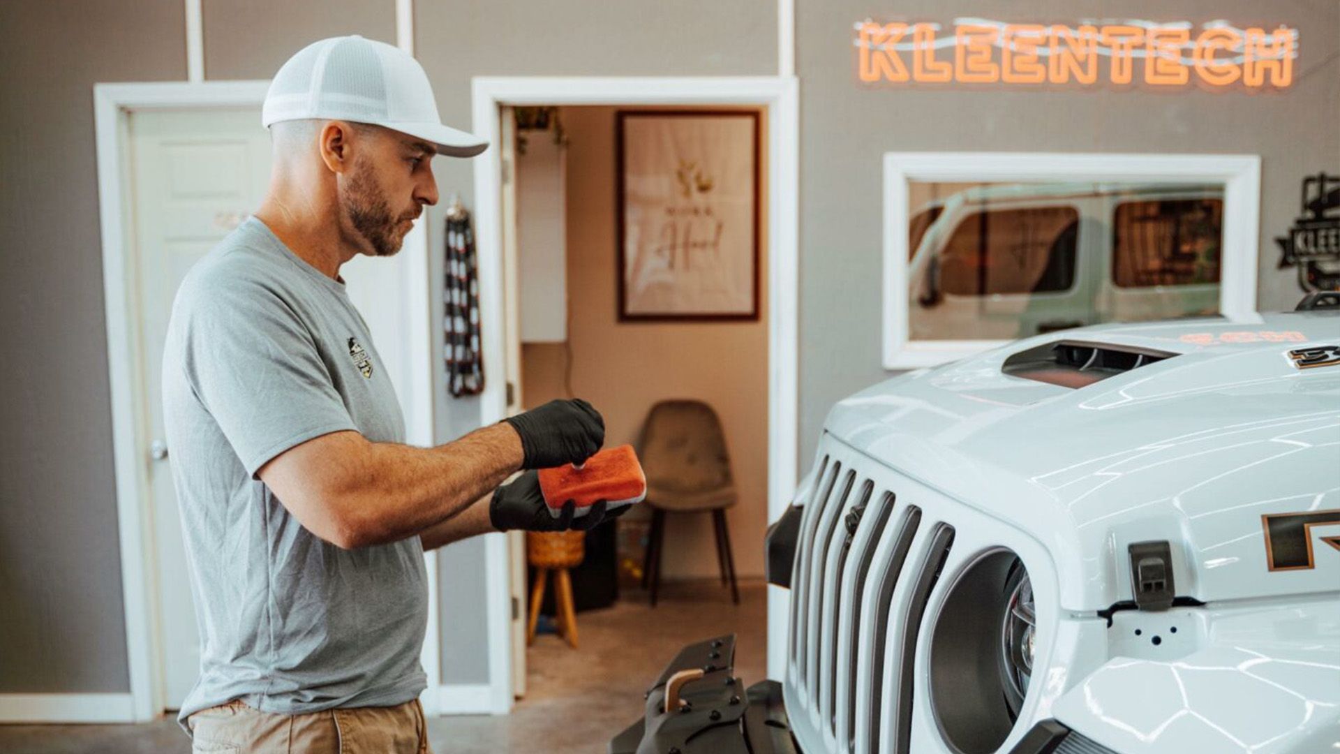 A man is cleaning the hood of a white jeep.