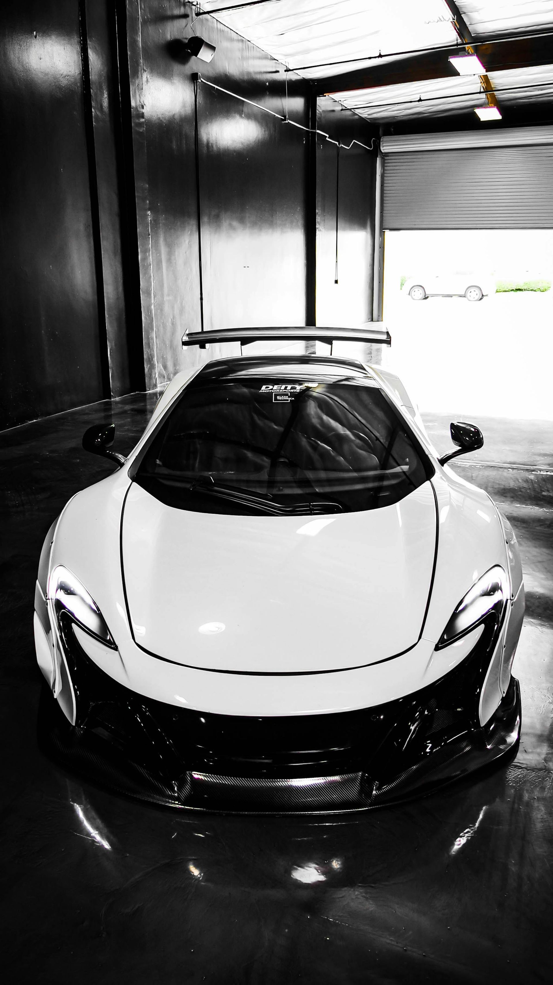 A black and white photo of a white sports car parked in a garage.