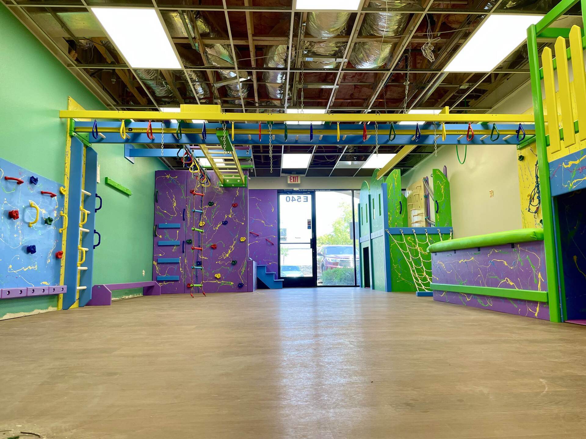 Commercial sensory gym with overhead climbing equipment, padded flooring, and custom indoor play structures
