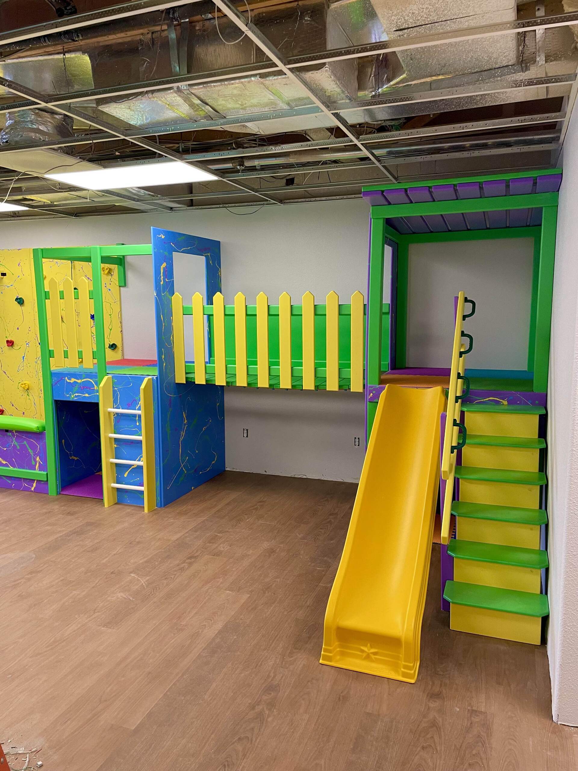 Commercial sensory gym with colorful wall panels, railing, climbing features, and custom play structure