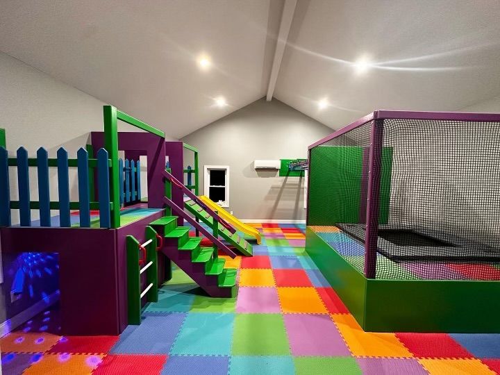 Indoor sensory gym with multicolored padded foam flooring, trampoline enclosure, and movement equipment