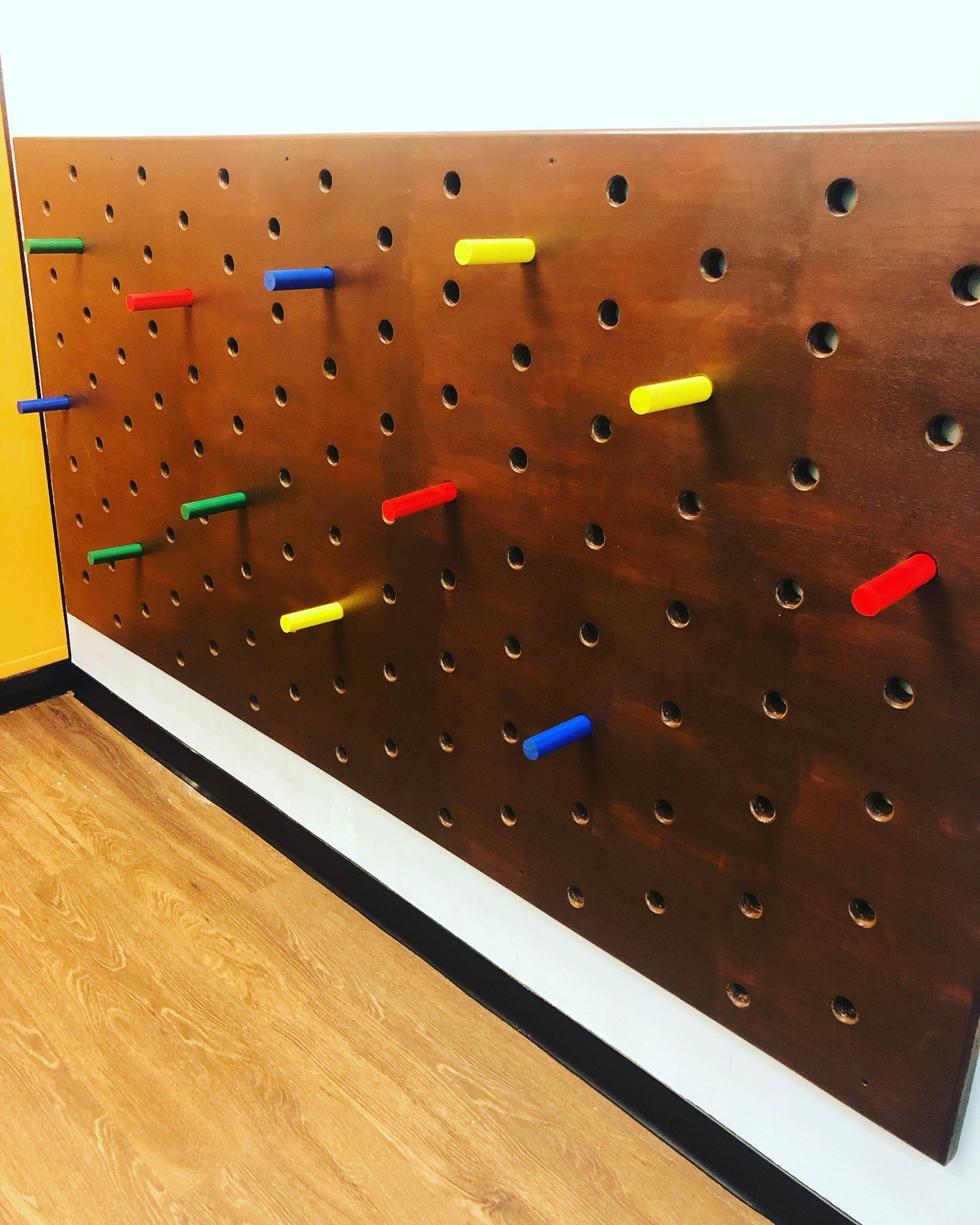 Custom sensory gym peg wall with colorful handholds for climbing, grip strength, and motor skill development