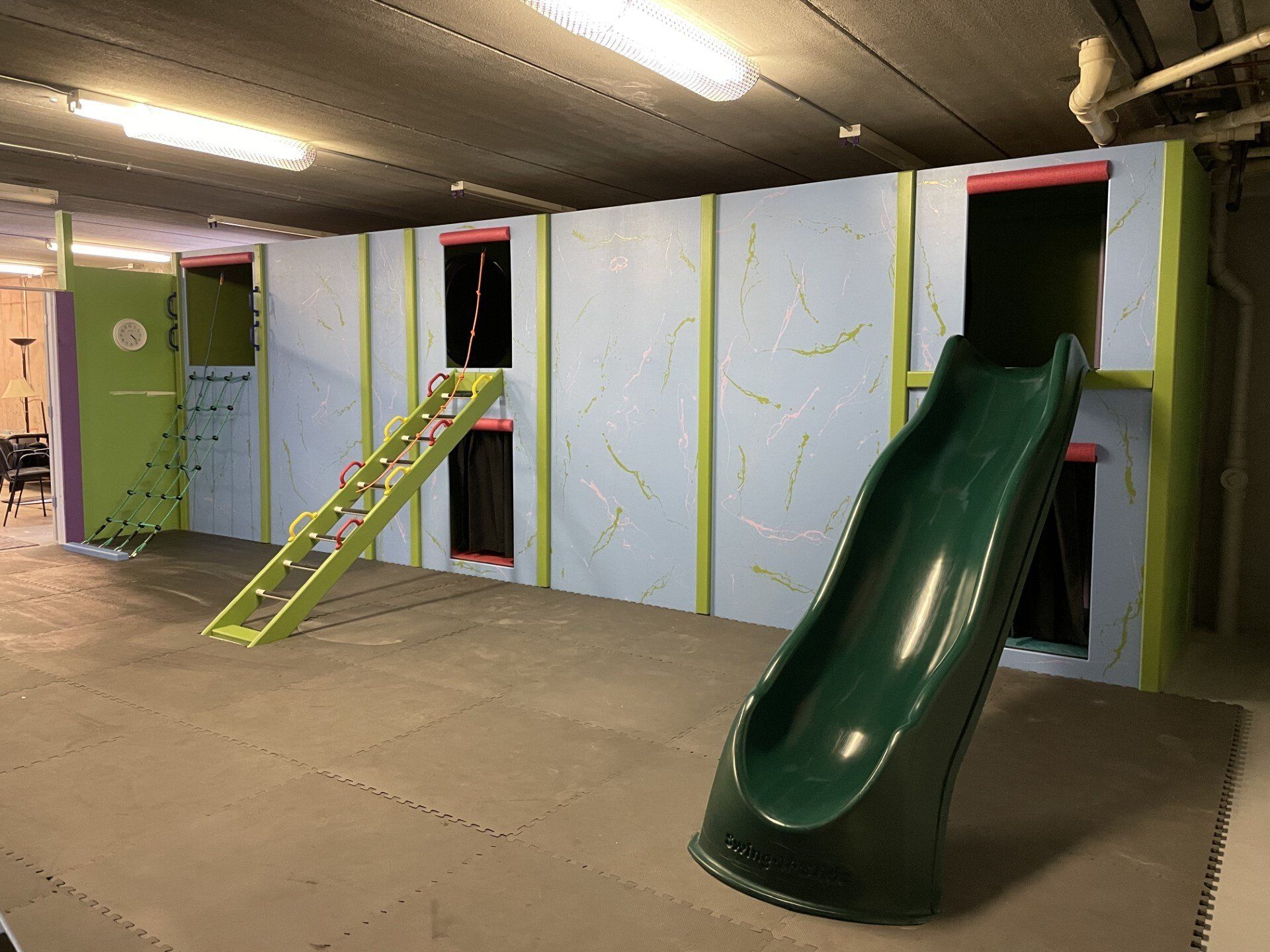 Commercial sensory gym with climbing wall, ladder, slide, and padded indoor movement equipment