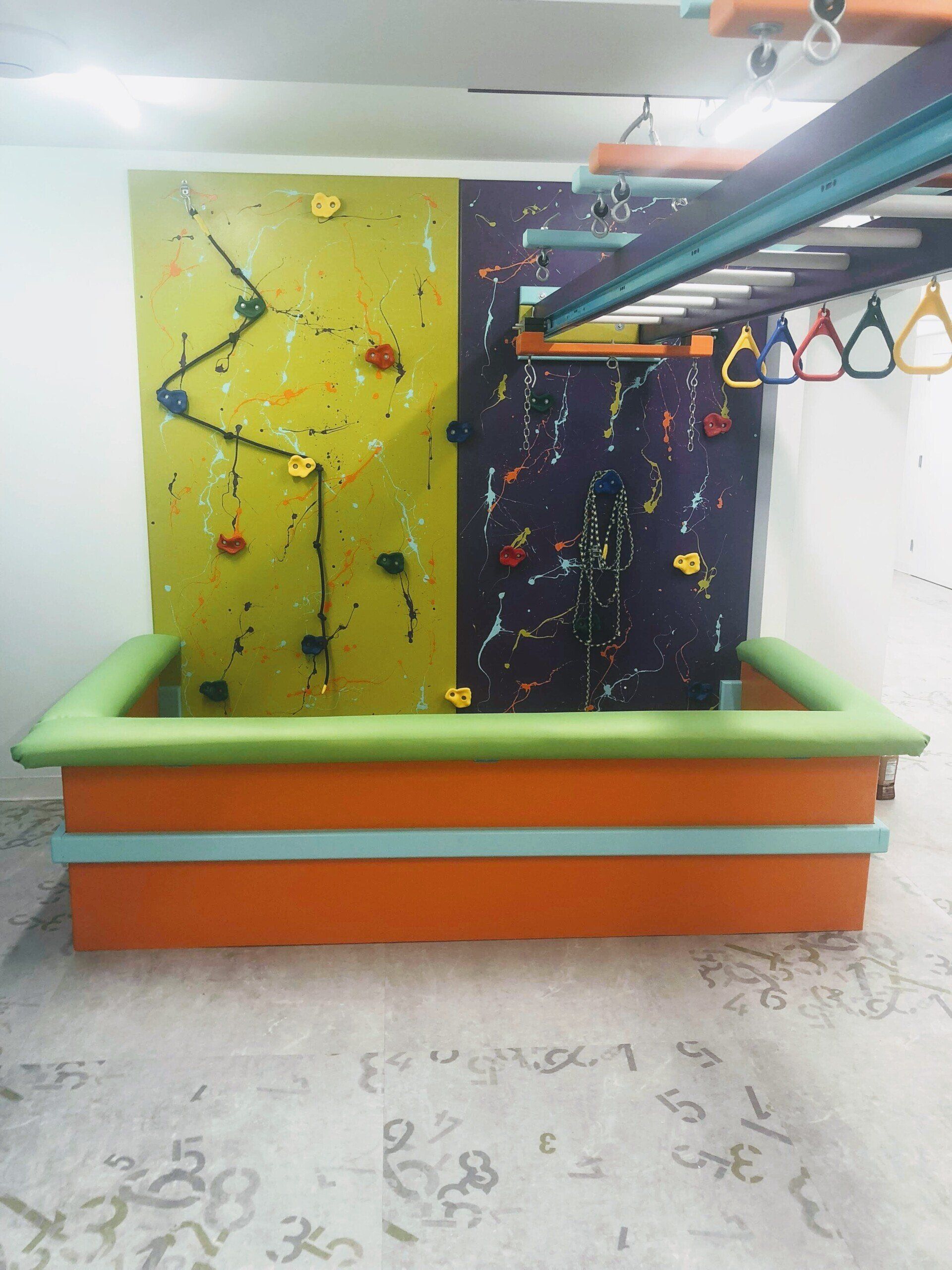 Custom sensory gym with climbing wall, overhead rings, padded flooring, and movement-based therapy equipment