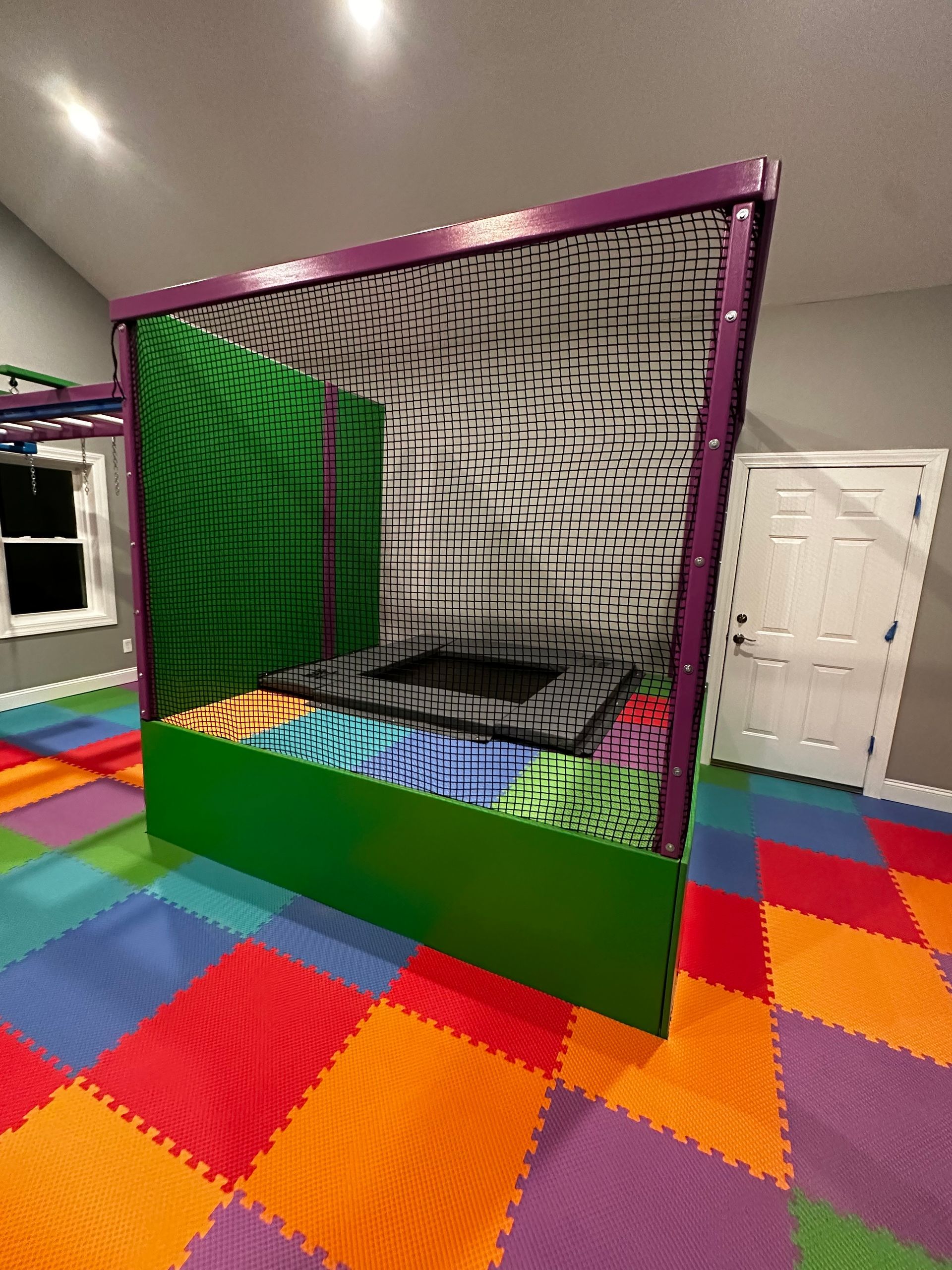 Custom sensory trampoline enclosure with safety netting, padded frame, and indoor therapy gym features