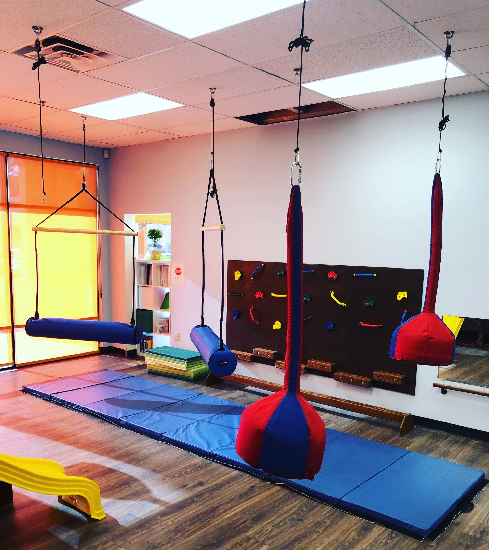 Indoor sensory gym with hanging swings, padded flooring, and equipment for sensory movement activities