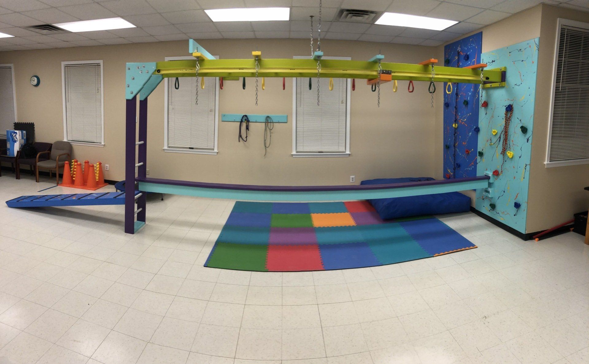 Custom sensory gym room with monkey bars, padded flooring, swings, and movement therapy equipment