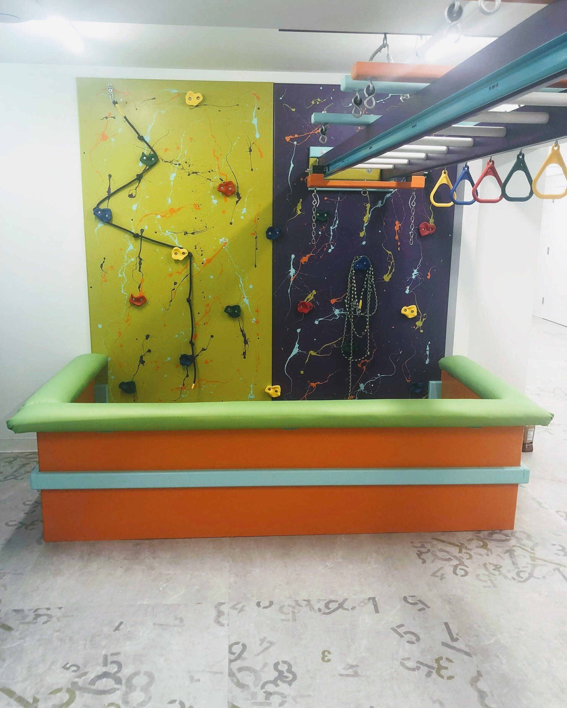 Custom sensory gym with climbing wall, overhead rings, monkey bars, and padded movement equipment