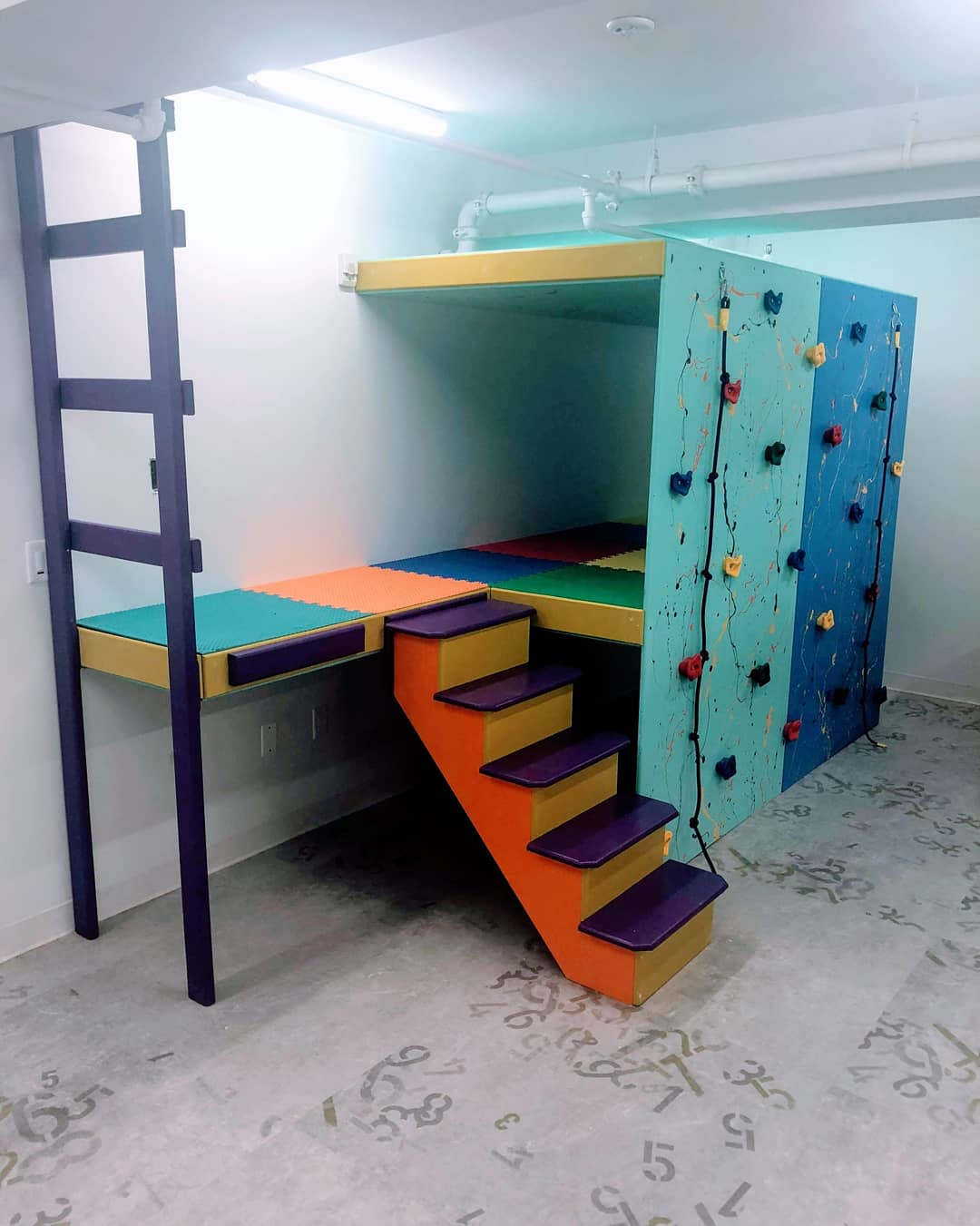 Custom sensory gym structure with climbing wall, padded platform, ladder, and indoor play features